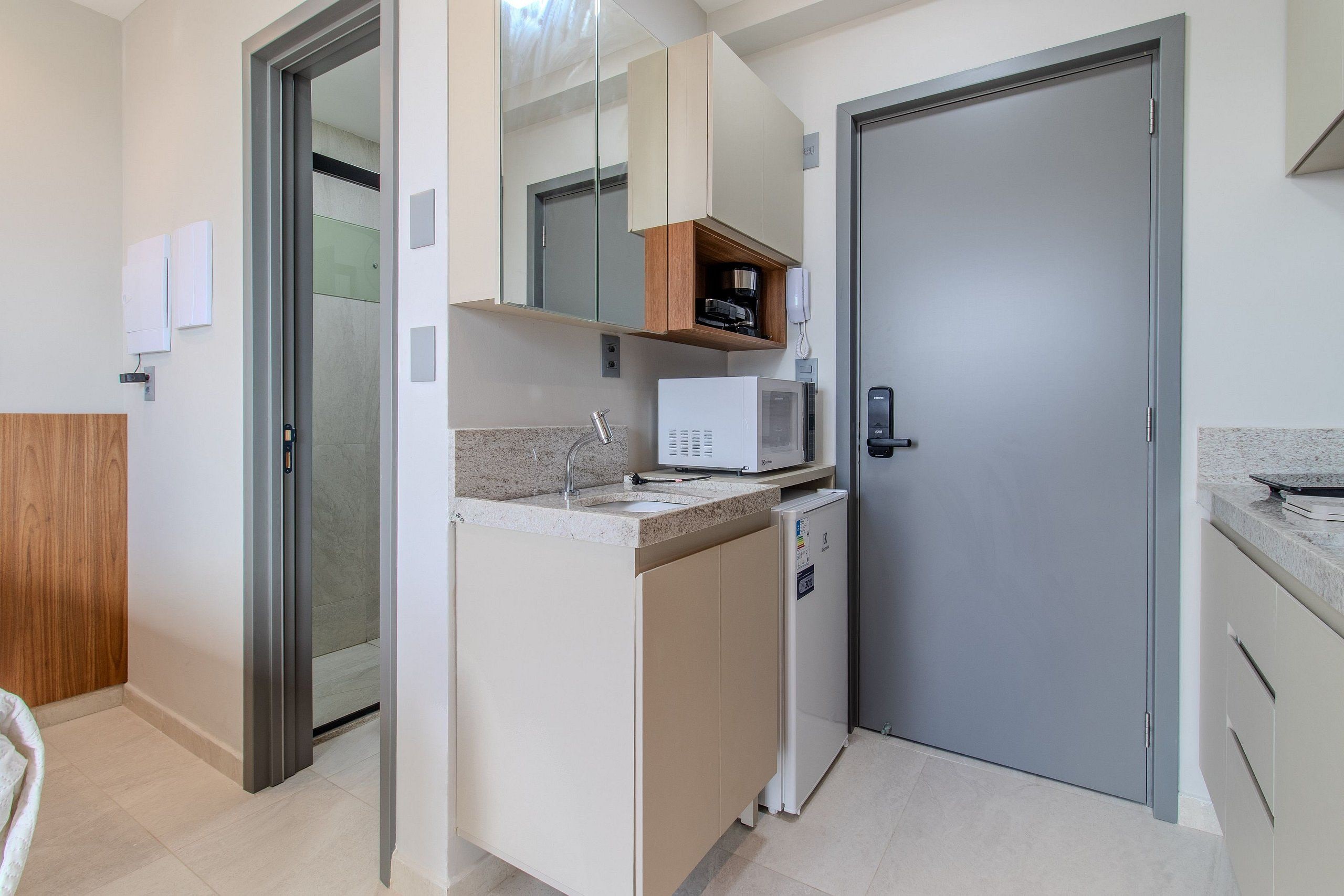 A compact kitchen with a microwave, a small refrigerator, and a built-in oven.