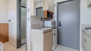 A compact kitchen with a microwave, a small refrigerator, and a built-in oven.