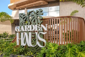 Et skilt med ordene 'GARDEN HOUSE' i store bogstaver, omgivet af grøn vegetation.