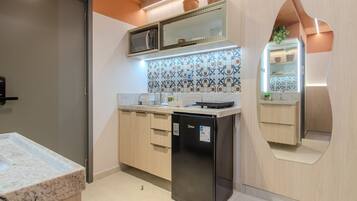 A modern kitchen with a built-in refrigerator, microwave, and a unique curved mirror design.