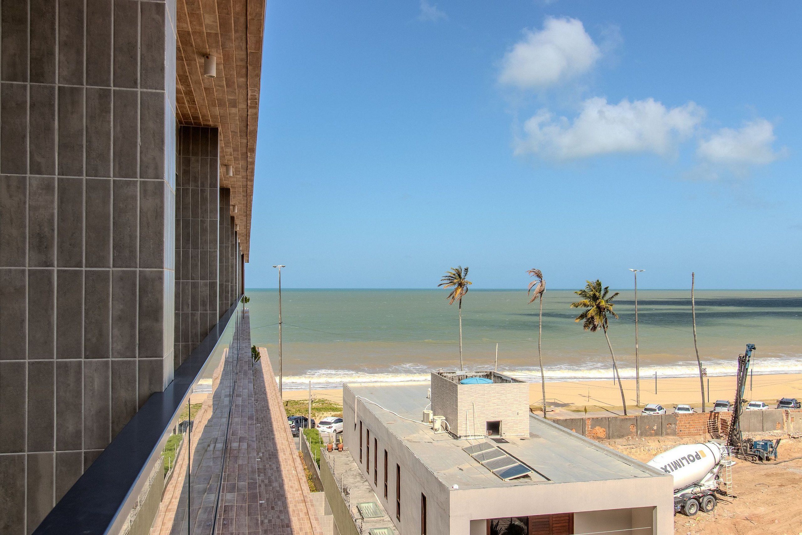 Vista de uma praia com palmeiras e céu claro.