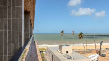 Vista de uma praia com palmeiras e céu claro.