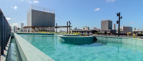 Piscina no terraço com paisagem urbana ao fundo.