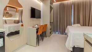 Ein Hotelzimmer mit einem Bett, einem Schreibtisch mit Stühlen, einem Fernseher und einem Spiegel.