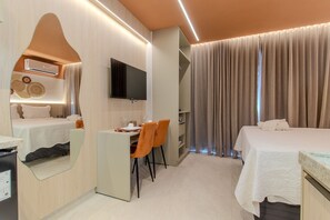 Ein Hotelzimmer mit einem Bett, einem Schreibtisch mit Stühlen, einem Fernseher und einem Spiegel.