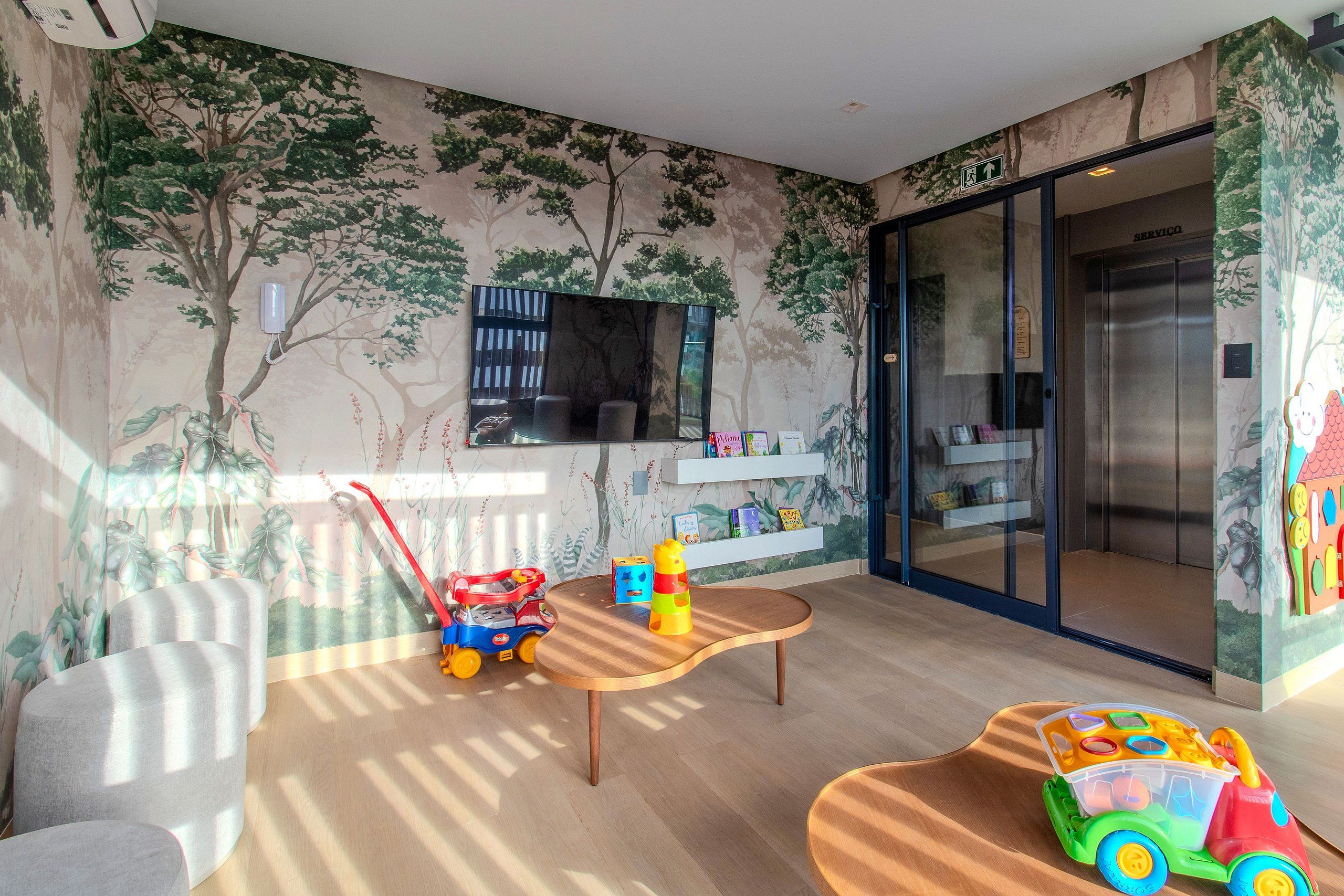 Quarto com televisão, mesa, cadeiras, um caminhão de brinquedo e um carrinho.