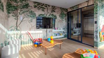 Quarto com televisão, mesa, cadeiras, um caminhão de brinquedo e um carrinho.
