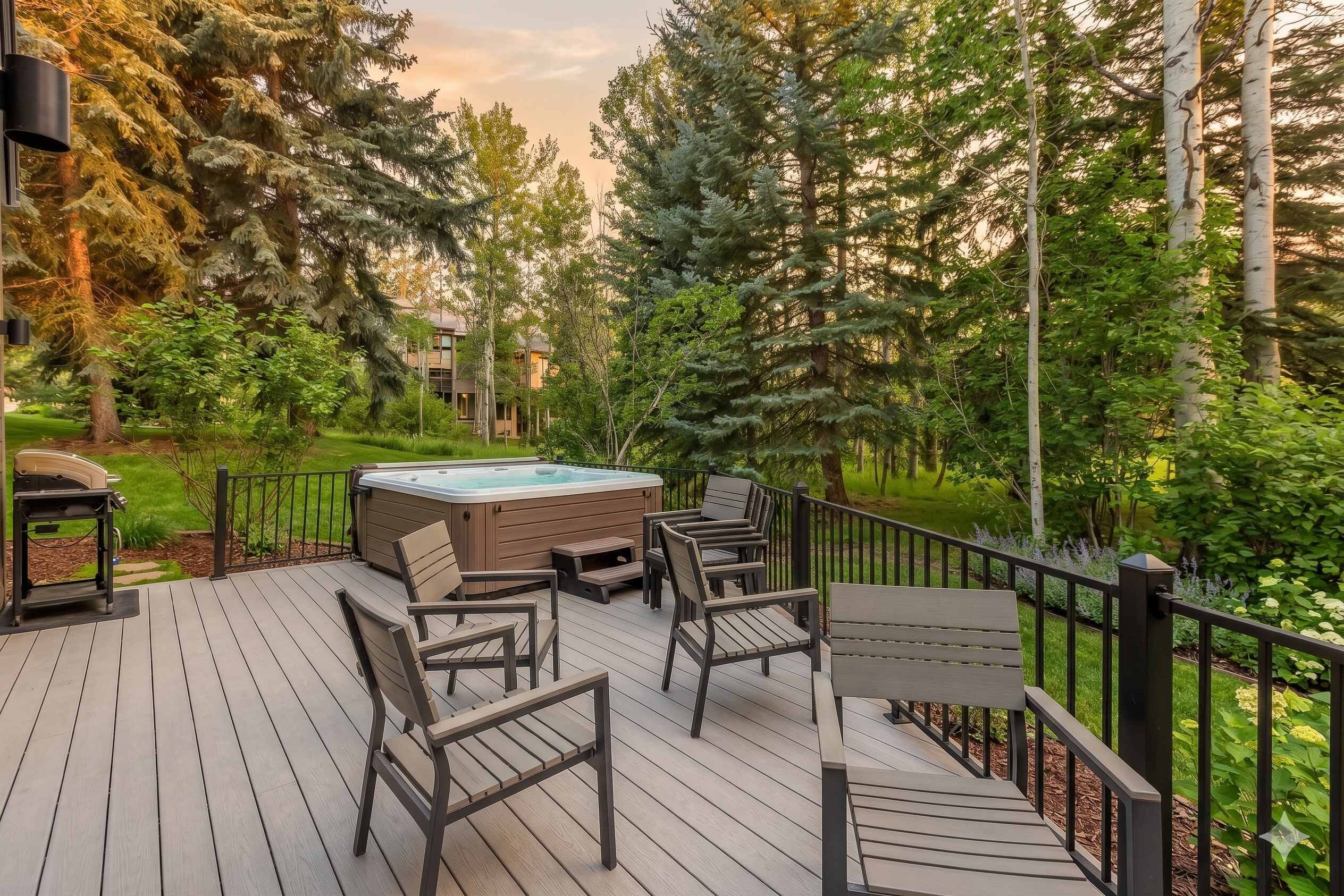 A deck with outdoor furniture, a hot tub, and a view of surrounding trees.
