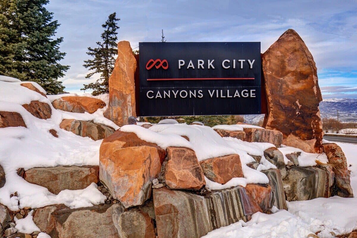 Un panneau indiquant l’entrée de Park City Canyons Village, avec un paysage montagneux en arrière-plan.