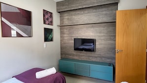 Un dormitorio con dos camas, un televisor, un armario de madera y una escalera.