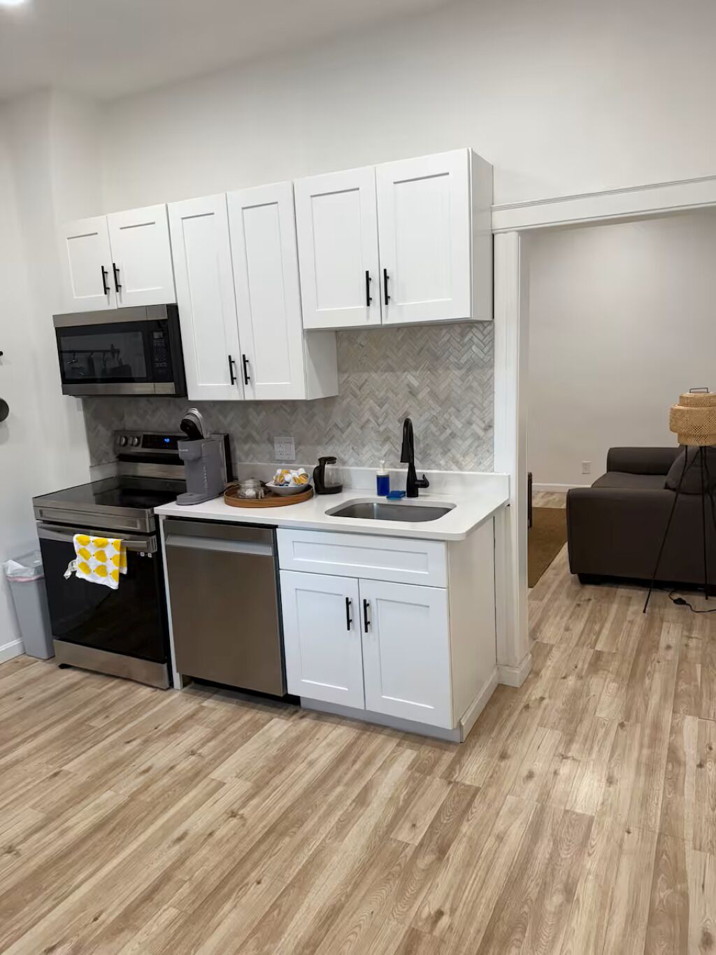 A modern kitchen with white cabinets, a microwave, oven, and dishwasher.