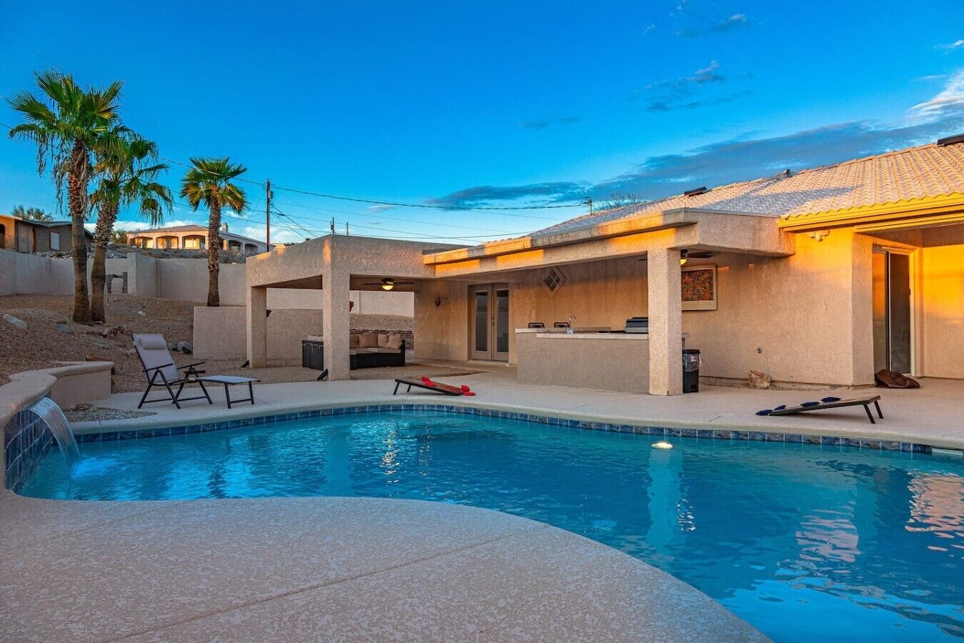 A swimming pool with lounge chairs, a bar area, and palm trees.