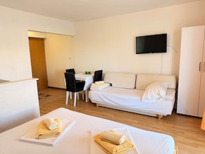 Ein Hotelzimmer mit zwei Betten, einer Couch, einem Esstisch und einem Fernseher.