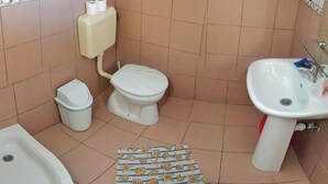 Kylpyhuone, jossa on wc, pesuallas, bidee ja roskakori.