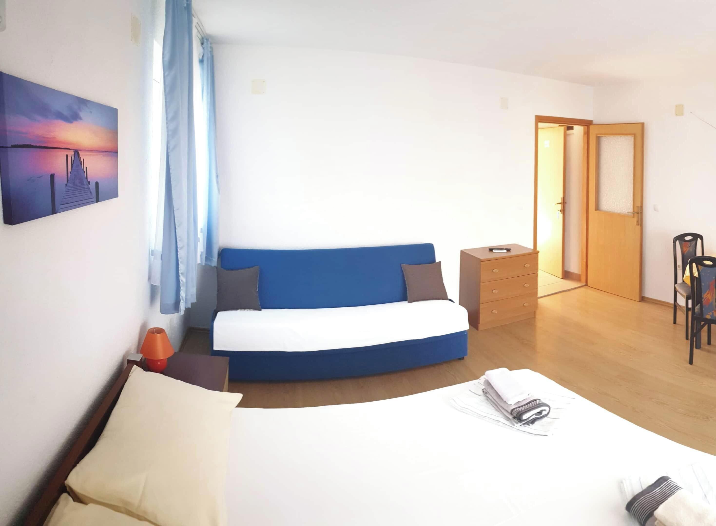 Un dormitorio con cama, escritorio, silla, armario y un cuadro en la pared.