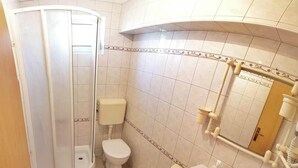 Ein Badezimmer mit Dusche, Toilette, Waschbecken und Spiegel.