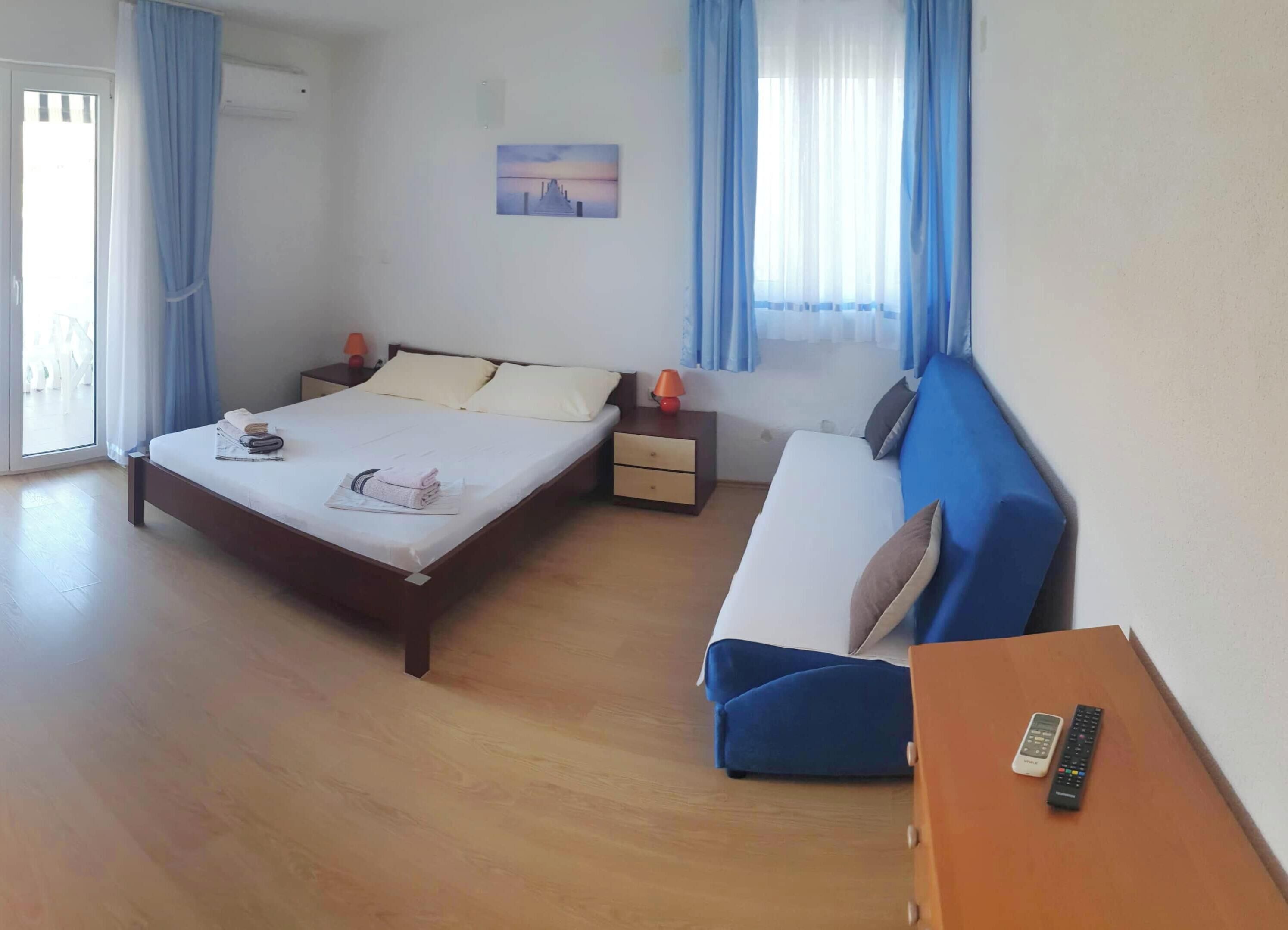 Une chambre d’hôtel avec un lit, un canapé, une table de chevet, une lampe et un tableau au mur.