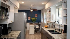 Una cocina equipada con microondas, refrigerador, estufa y ventilador de techo.