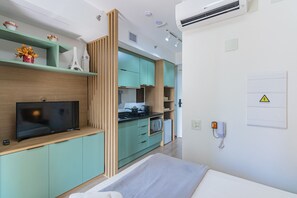 Eine moderne Küche mit Flachbildfernseher, Holzschränken und einer Mikrowelle.