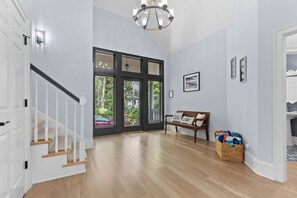 A spacious hallway with a staircase, large windows, a bench, and a wicker basket. - Golf Views, Pool Table, Free Pools, Walk to Beach (Seabrook Island)