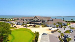 A large building with a golf course in front, a parking lot, and a view of the ocean. - Golf Views, Pool Table, Free Pools, Walk to Beach (Seabrook Island)