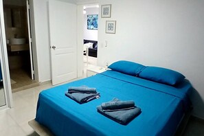 Ein Schlafzimmer mit einem Bett, Kissen und gefalteter Kleidung auf dem Bett.