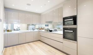 A modern kitchen with a large island, built-in appliances, and a view of the dining area.