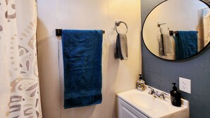 Un bagno con portasciuga asciugamani, un lavandino con erogatore di sapone e uno specchio.