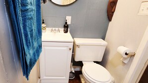 Un bagno con il water bianco, un lavandino con erogatori di sapone, un asciugamano blu e uno specchio.