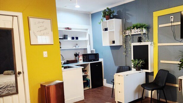 Un ambiente compatto con angolo cottura, una piccola area studio, un letto e un termosifone.