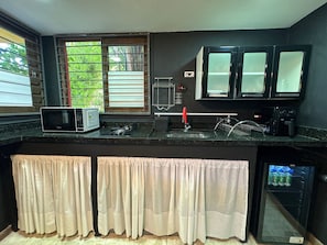 A kitchen with a microwave, gas stove, sink, and cabinets.