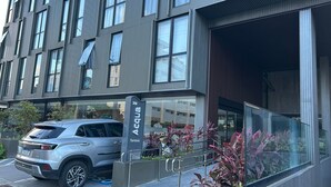 En moderne bygning med stor glasseftergang, en parkeret SUV og et skilt med navnet 'Acqua'.