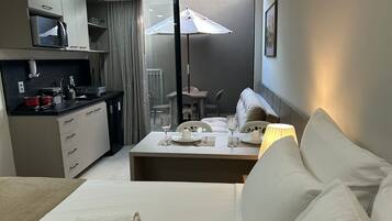 A modern hotel room with a kitchenette, a dining area, and a sofa.
