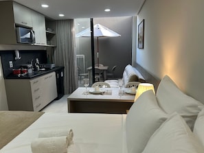 A modern hotel room with a kitchenette, a dining area, and a sofa. - Bela Hospedagem - Acqua Tambaú Flat   (João Pessoa)