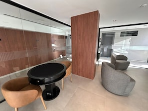 A modern interior with a round table, two chairs, a wooden partition, and a grey armchair. - Bela Hospedagem - Acqua Tambaú Flat   (João Pessoa)