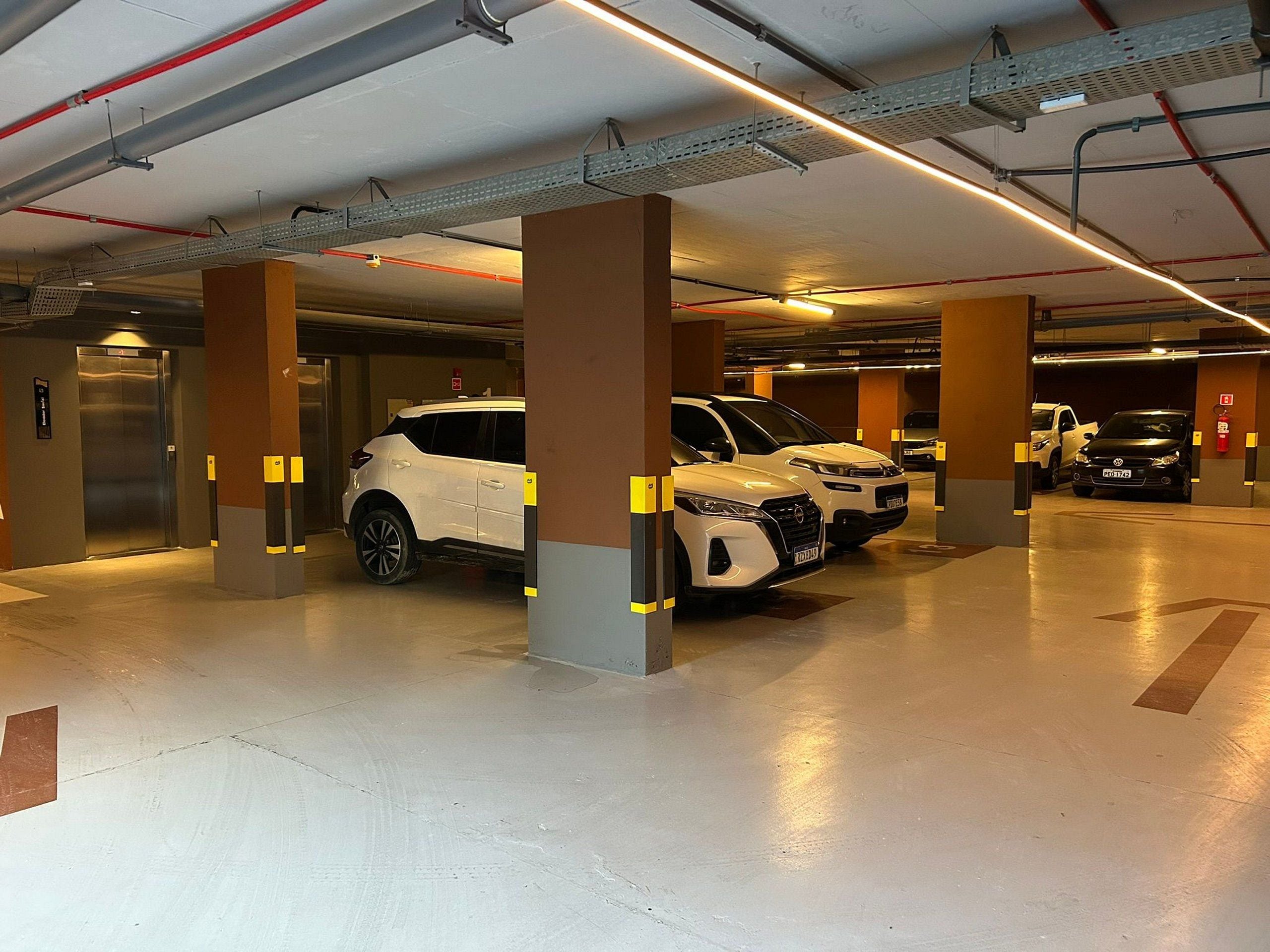 Eine mehrstöckige Parkgarage mit Autos, Säulen und Deckenbeleuchtung.