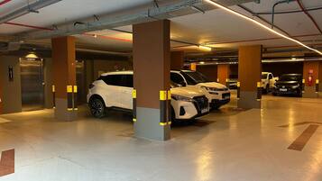 Eine mehrstöckige Parkgarage mit Autos, Säulen und Deckenbeleuchtung.