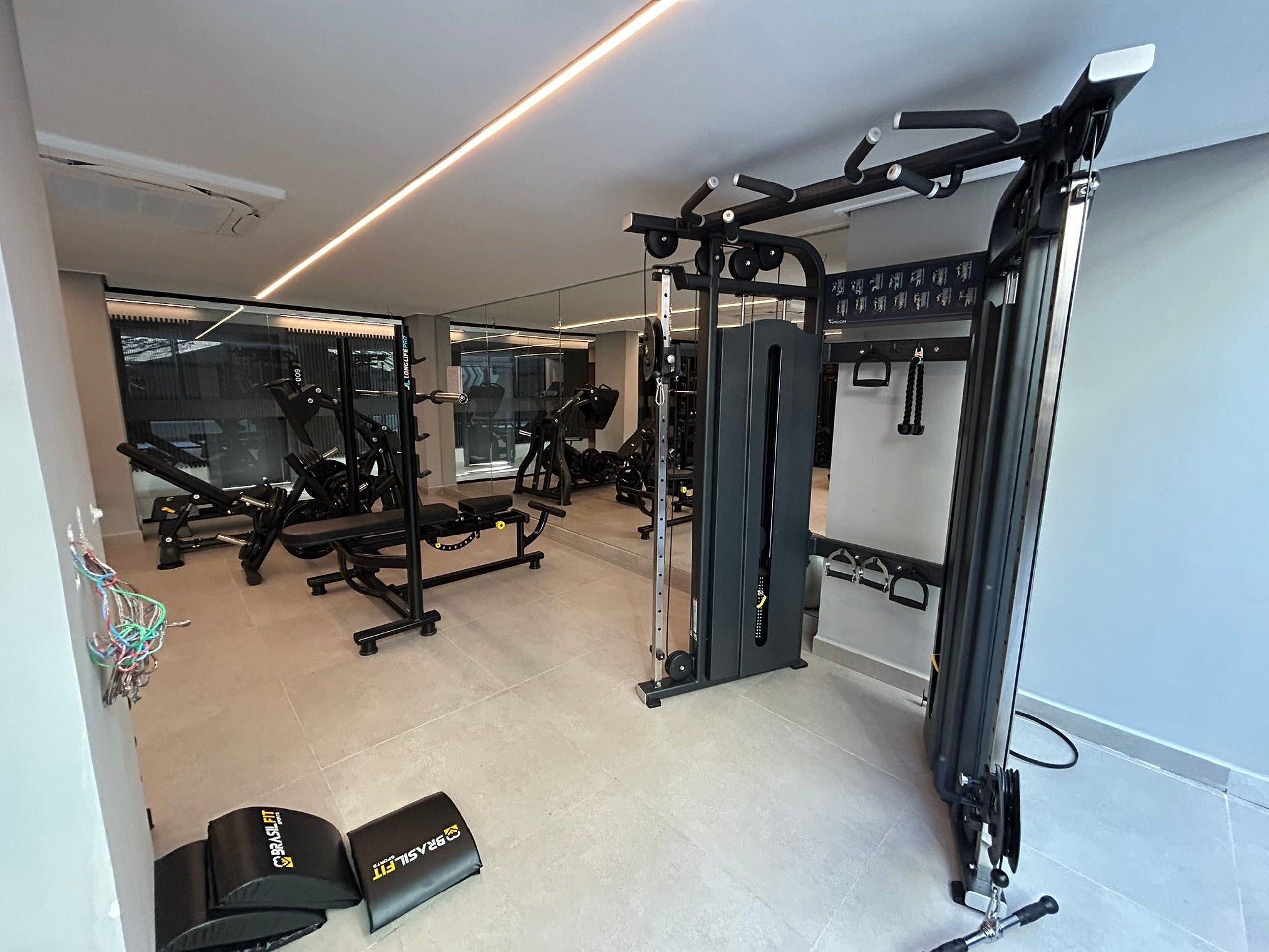 A gym with exercise equipment, a bench, and a mirror.