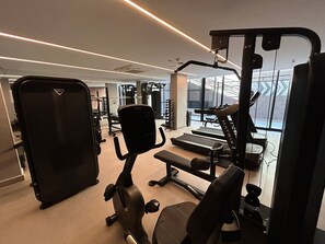Ein Fitnessraum mit Trainingsgeräten, Laufband und Spiegelwand.