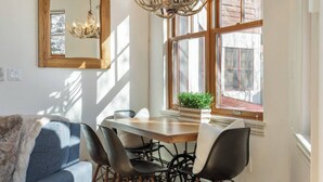 Comedor con mesa de madera, sillas negras y candelabro.