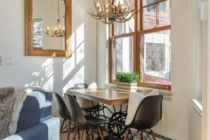 Ein Essbereich mit Holztisch, schwarzen Stühlen und einer Chandelier.