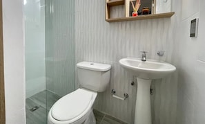 Ein Badezimmer mit Toilette, Waschbecken und einer Duschkabine aus Glas.