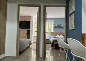 Ein geräumiges Zimmer mit einem Bett, einem Schreibtisch und einem Stuhl, mit Blick auf eine blaue Wand und ein Fenster.