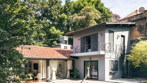 A modern two-story house with a balcony, a patio with outdoor furniture, and a garden. - Charming & Spacious Home w/ Garden | 2BR (Carapicuíba)