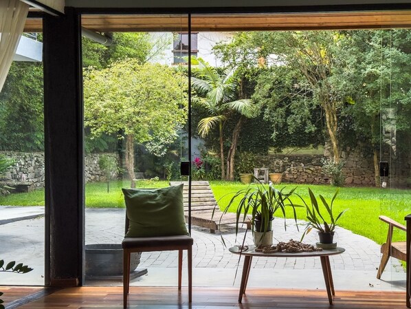 Un interior moderno con un amplio ventanal que da a un jardín bien cuidado.