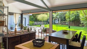 A modern kitchen with a dining area, large windows, and a view of a lush garden. - Charming & Spacious Home w/ Garden | 2BR (Carapicuíba)