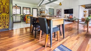 A spacious living area with a high ceiling, wooden flooring, and a central dining table with chairs. - Charming & Spacious Home w/ Garden | 2BR (Carapicuíba)