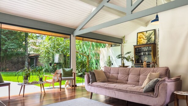 A spacious living area with a large window, a cushioned sofa, and a wooden coffee table. - Charming & Spacious Home w/ Garden | 2BR (Carapicuíba)