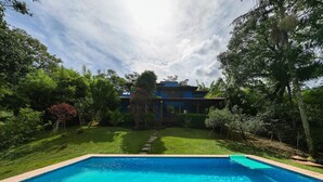 Una piscina con agua cristalina, rodeada de un césped cuidado y árboles.