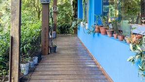 Una terraza cubierta de madera con plantas en macetas y una pared azul.